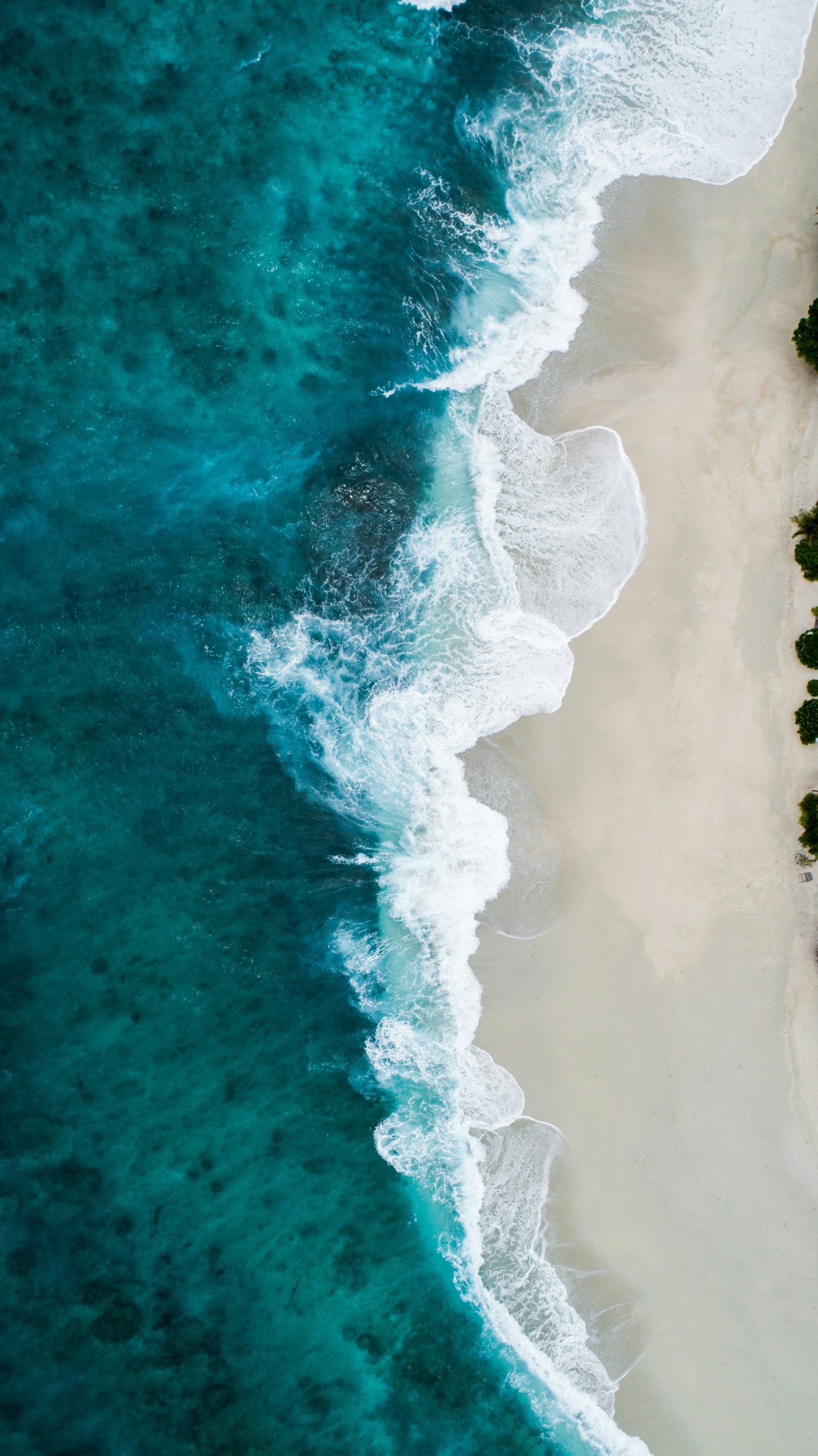 Aerial view of surf meeting white sand