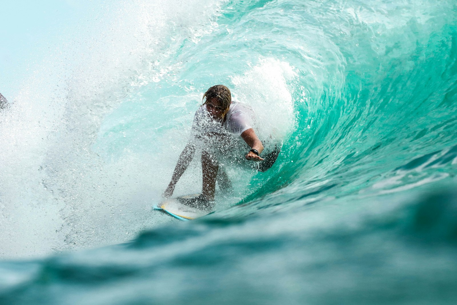 Surfer riding inside a turquoise barrel